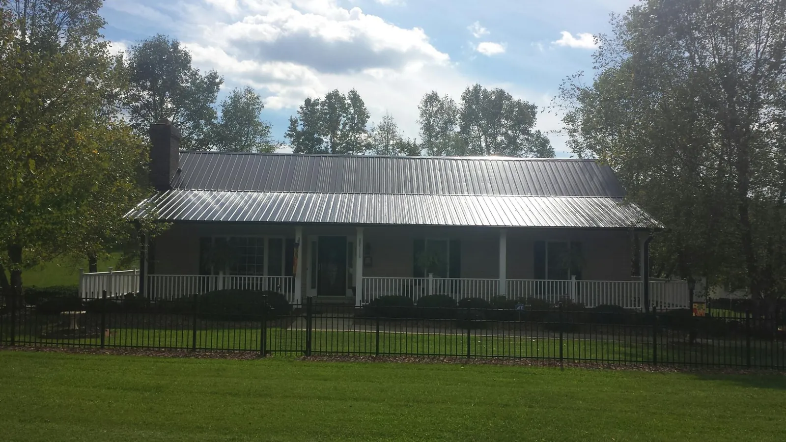 Gray metal roof on a brick ranch with a full width front porch — Gutter Guard Installation work by our crew in Clay